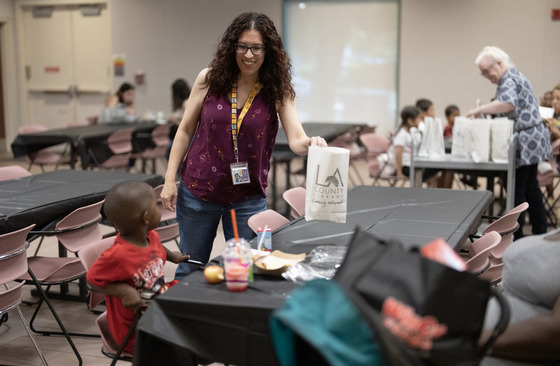 Lunch program with woman looking down at child sitting at a table