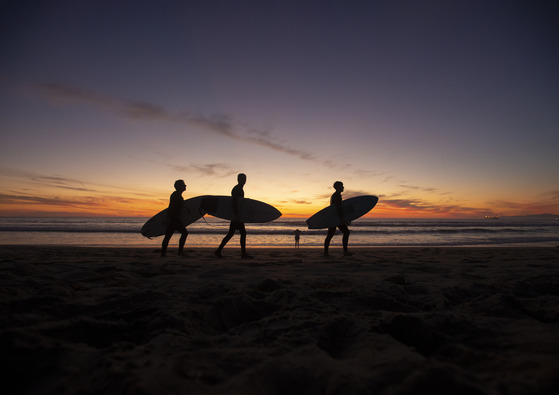 Manhattan Beach sunset with surfers walking