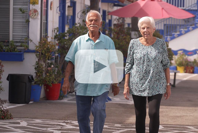 Older adult male walking next to his wife with a motel building behind them