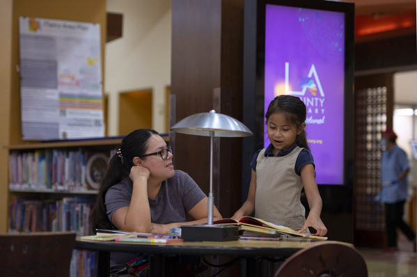 Mother and daughter together at a table with a stack of books