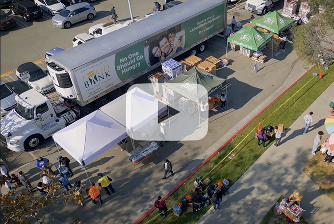 Ariel view of canopies, people, big rig truck, boxes of food getting set up at a parking lot