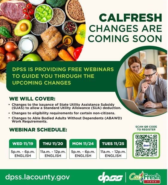 Male with glasses sitting down is looking at laptop with female standing next to him, and variety of food