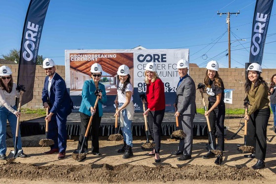 a group of people wearing hard hats and holding shovels at a groundbreaking ceremony 