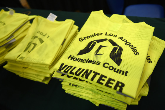Stack of yellow vest jackets that say Greater Los Angeles Homeless Count Volunteer with logo