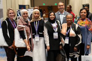 A group of women--some wearing hijabs smile at the camera while at the 2025 C4A Conference