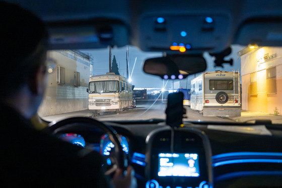 Male sitting in driver seat as he drives through street with recreation vehicles on the side during night time