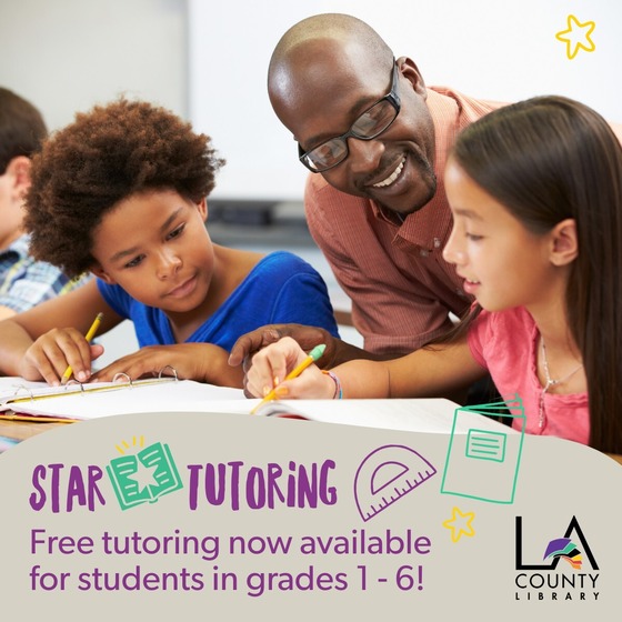 Man with glasses tutors two students as they do homework on a table