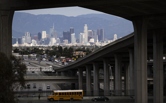 Downtown Los Angeles skyline along Harbor Freeway with yellow school bus on one of the street overpass.