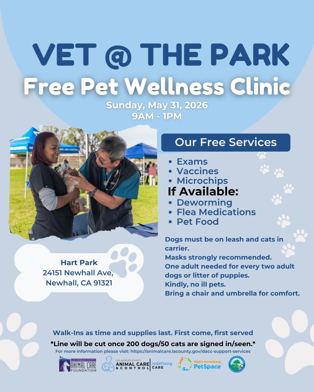Woman holds dog as male veterinary doctor checks dog at an open space with grass and canopies