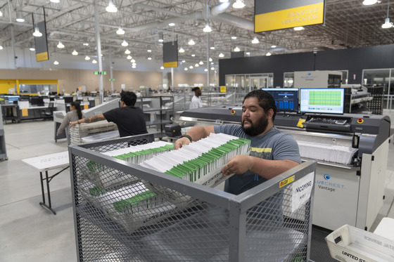 Man getting vote by mail ballots from a cart at the Ballot Processing Center in the City of Industry