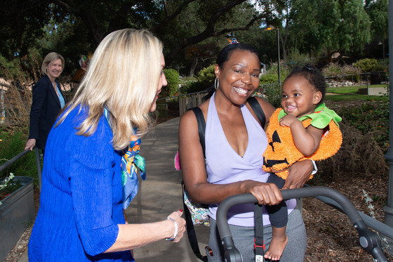 Supervisor Kathryn Barger speaks with a woman holding a baby in a pumpkin costume