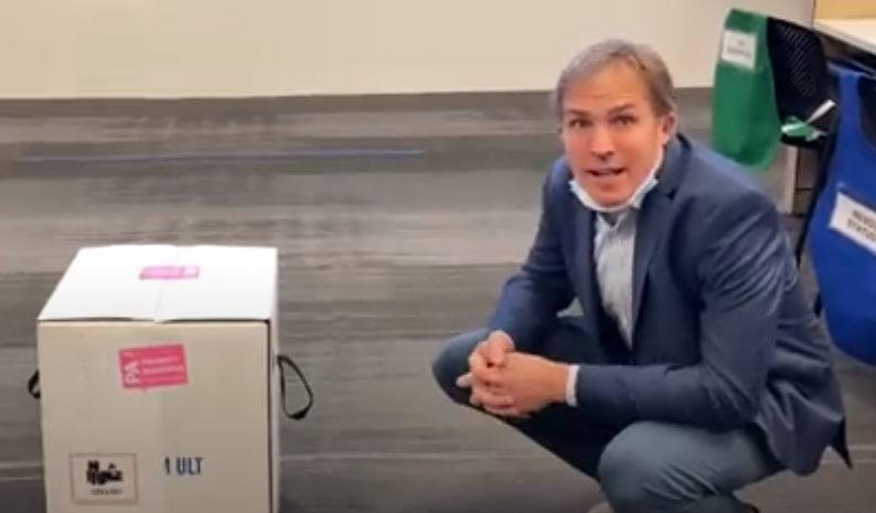 Dr. Matt Willis kneels next to the first box of COVID-19 vaccine doses to arrive in Marin County.