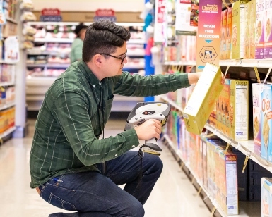 A male inspector checks the price of an item at a grocery store