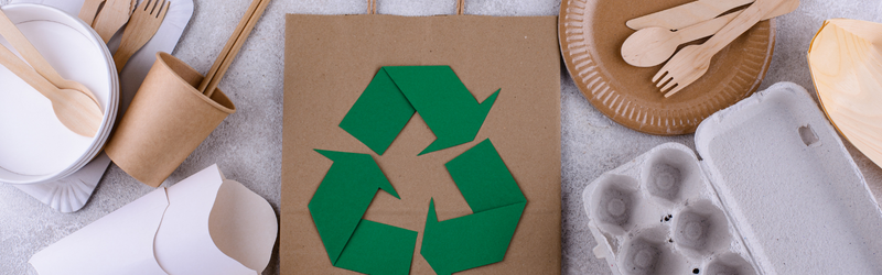 Image of compostable and reusable food ware with green recycling image on a paper bag
