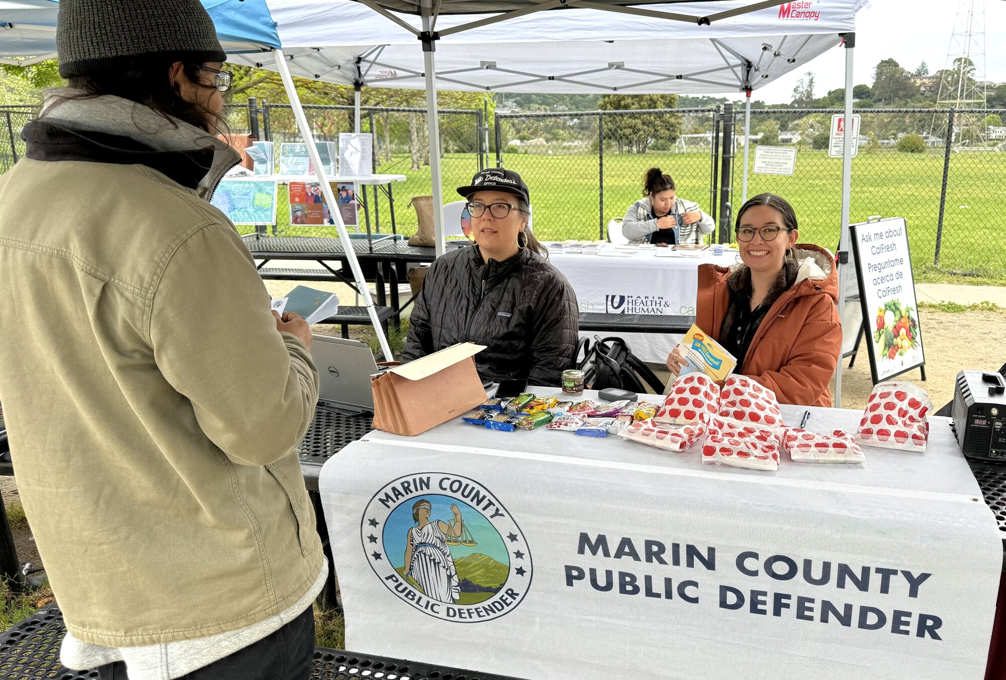 Two women sit at a table and represent the Public Defender's Office during a Clean Slate program event.