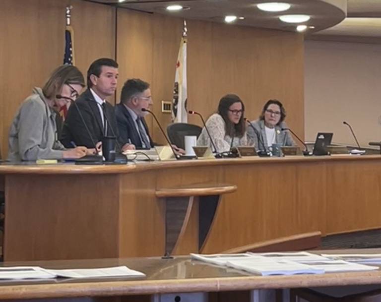 Supervisor Sackett speaking on dais sitting next to other Supervisors