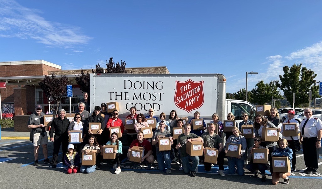 volunteers posing for group photo in front of Salvation Army truck with boxes full of clothes
