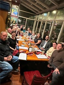 neighbors gathered around restaurant table smiling toward camera