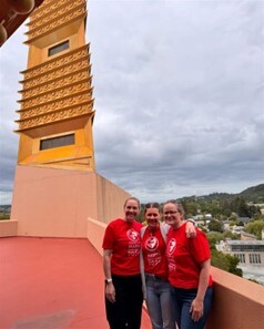 Mary and staff smiling toward camera in red heart walk shirts in front of Civic Center spire