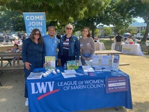 League of Women Voters table, group smiling behind table toward camera