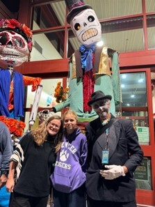 Smiling in front of paper mache skeletons