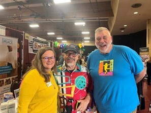 Smiling toward camera in aisle of tables in Exhibit Hal