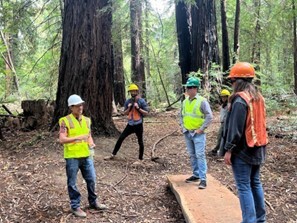Mary standing on redwood board walk talking to staff