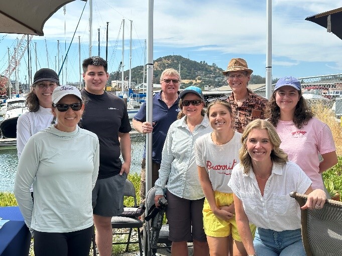 group smiling toward camera clustered together on boat dock