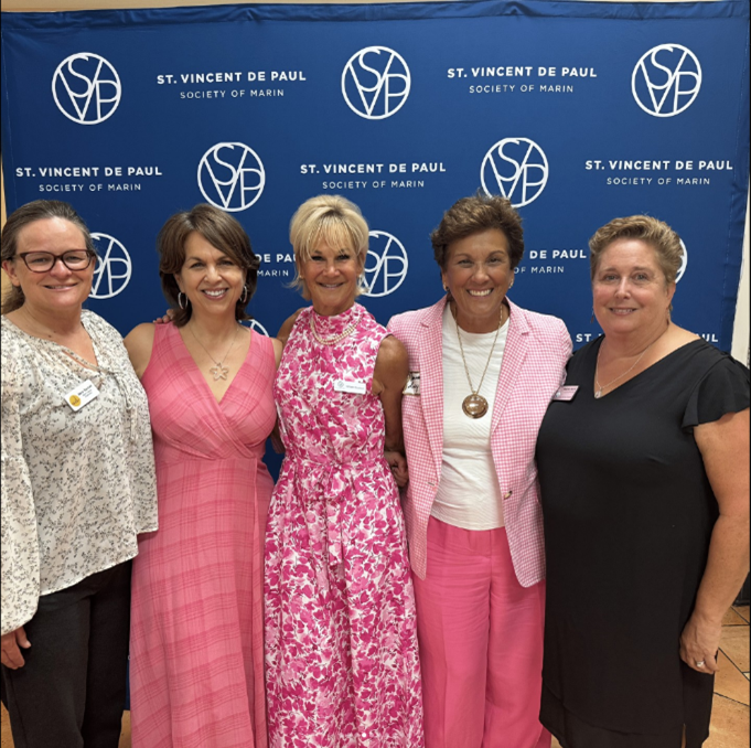 group arm and arm together smiling in front of photo wall