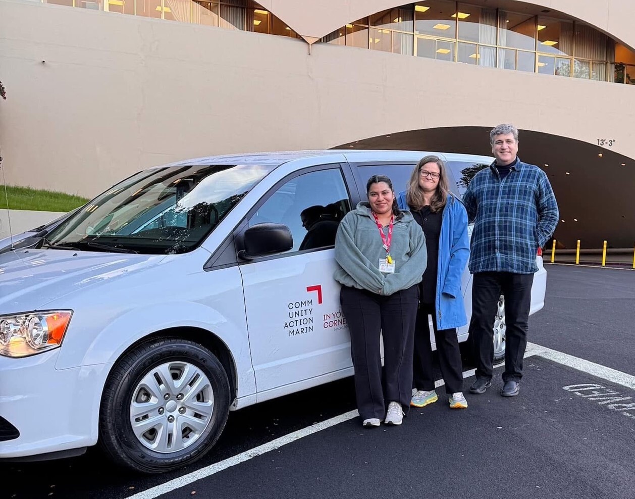 Smiling toward camera in front of civic center with two staff members