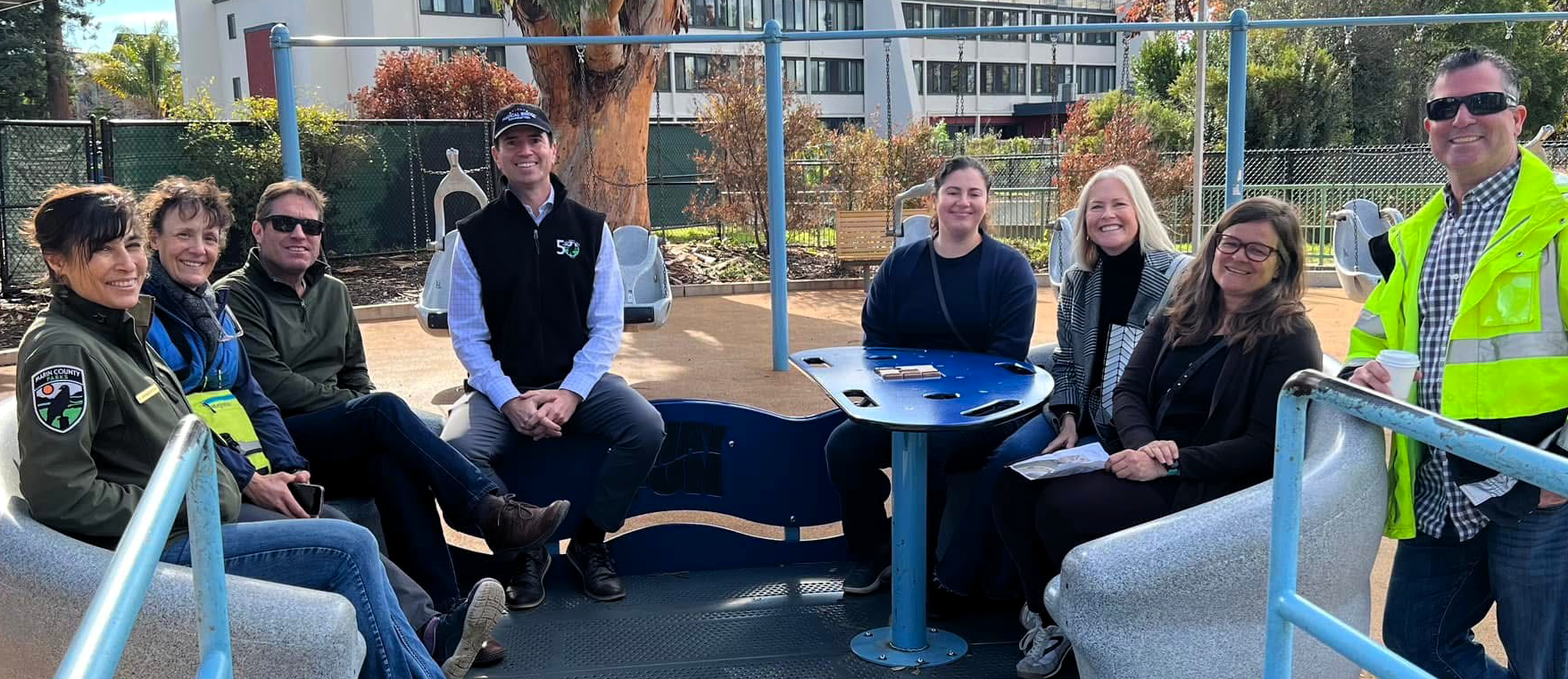 county staff sitting on accessible sea-saw smiling toward camera