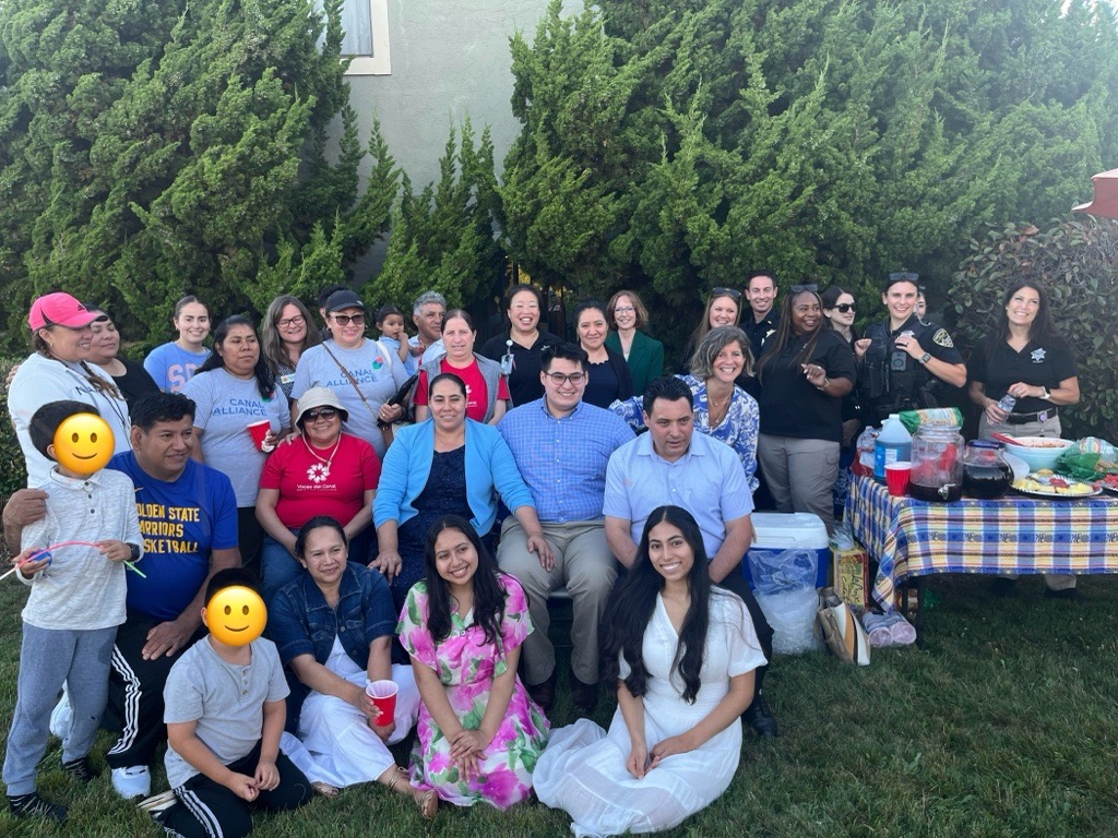 large group smiling toward camera on lawn in front of greenery