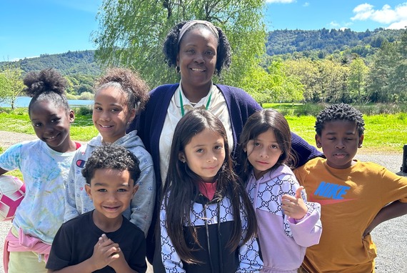 Six kids with a mentor smile at a county park.