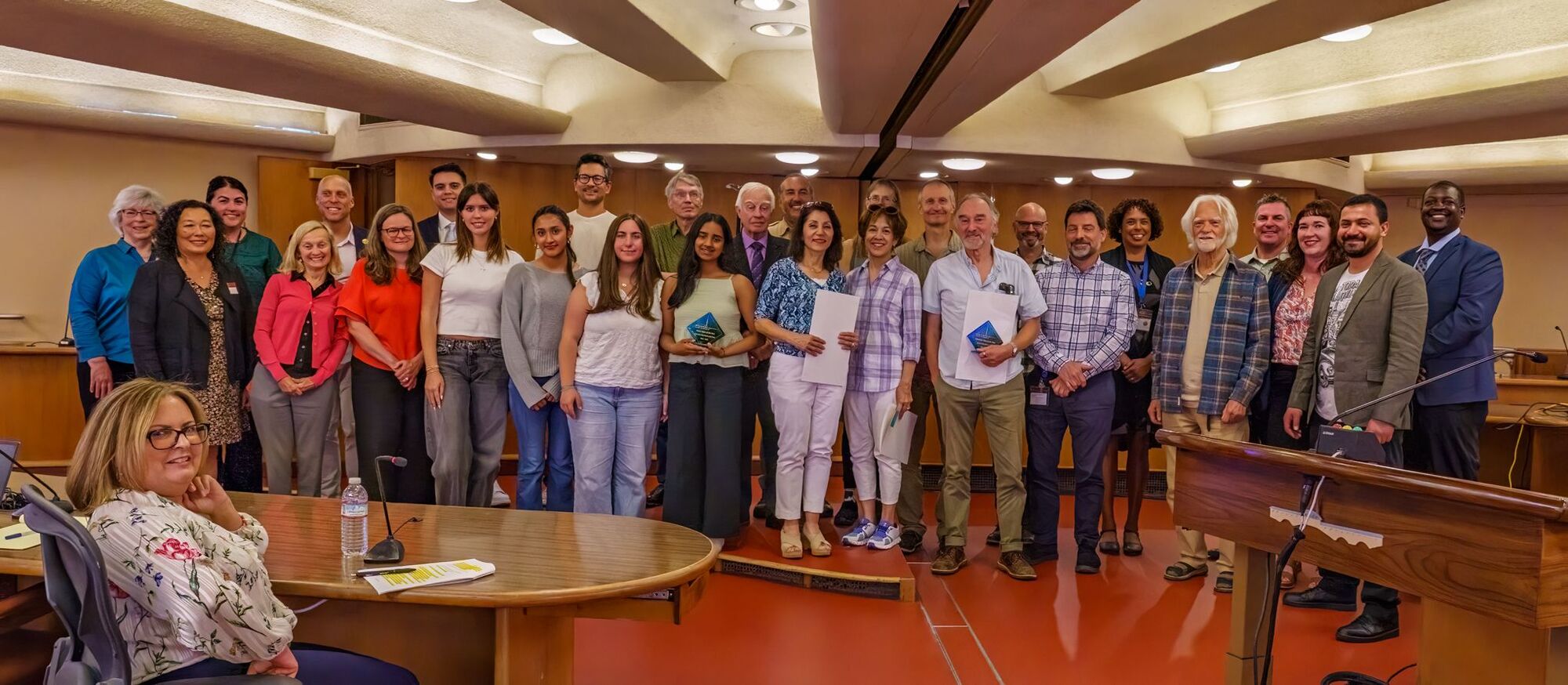 award recipients and staff smile on stage in Board chambers 