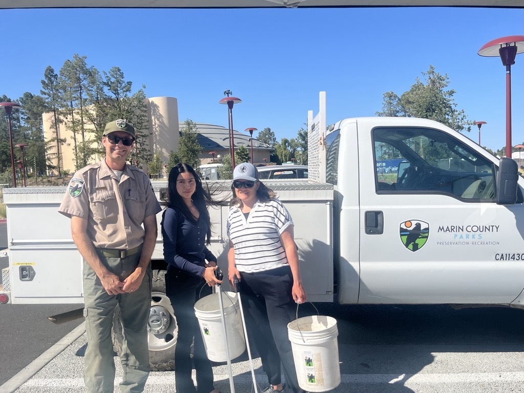 Kirk, Melanie, and Mary smile in front of Parks truck with clean-up tools