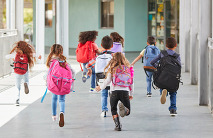 School kids with backpacks run in a school outdoor hallway