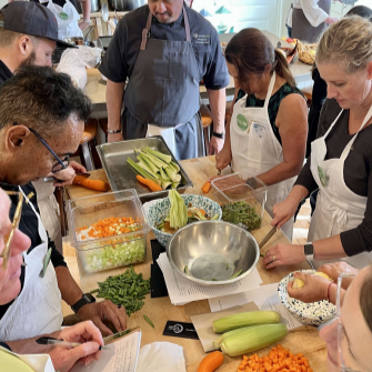 group of people around kitchen table chopping celery and carrots