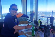 A woman smiles at a wildfire lookout station on a mountaintop office.