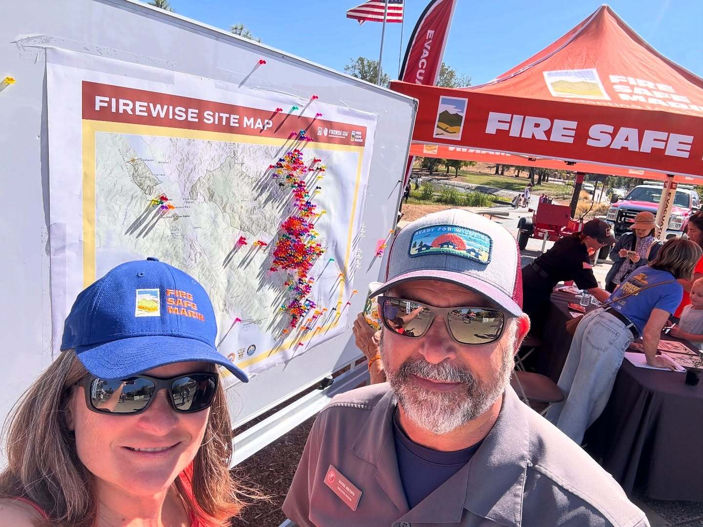 Mary smiling with Mark Brown at Emberstomp in front of FireSafe tent