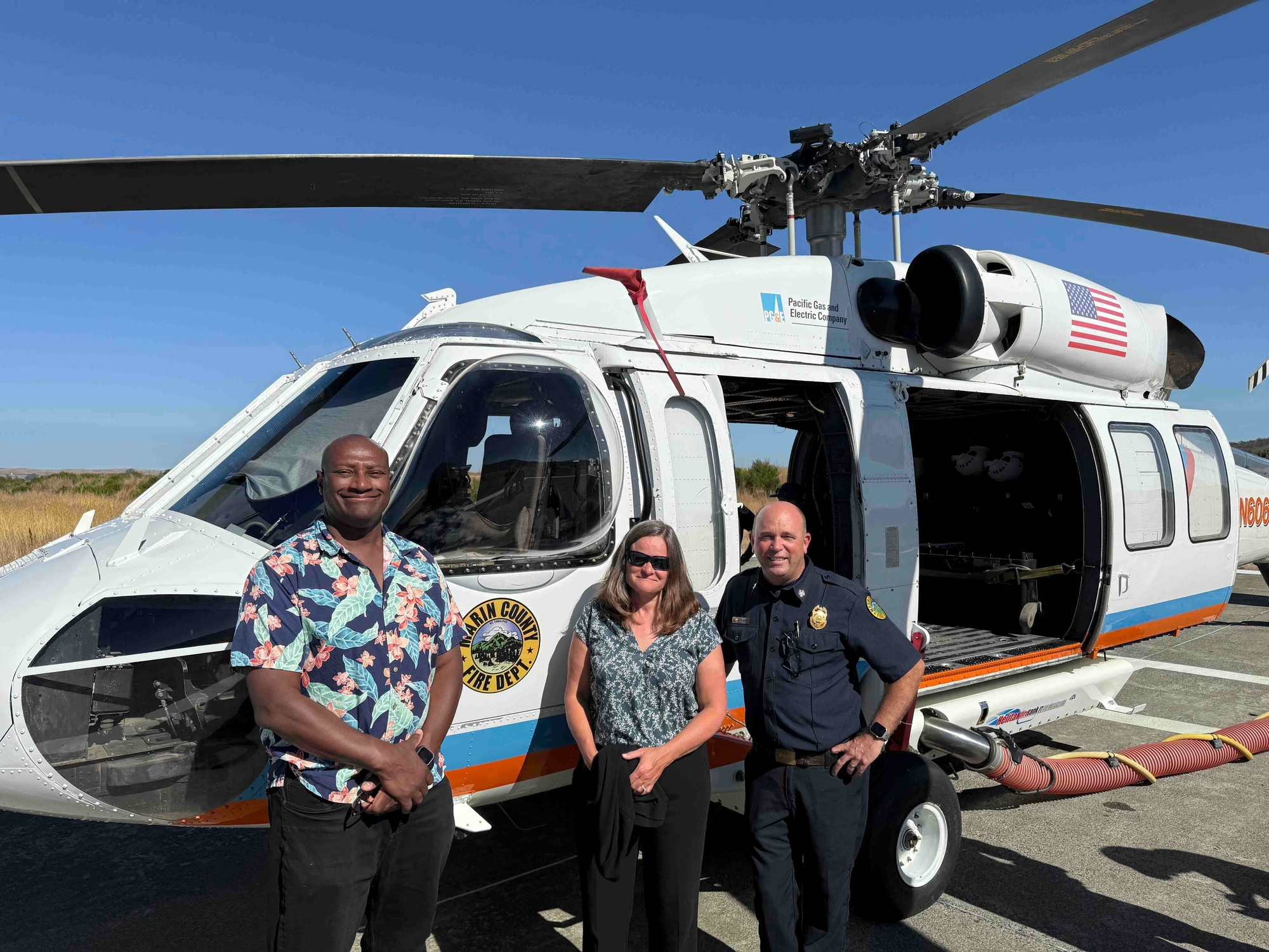 Mary, Brian, and Chief Weber standing in front of helicopter