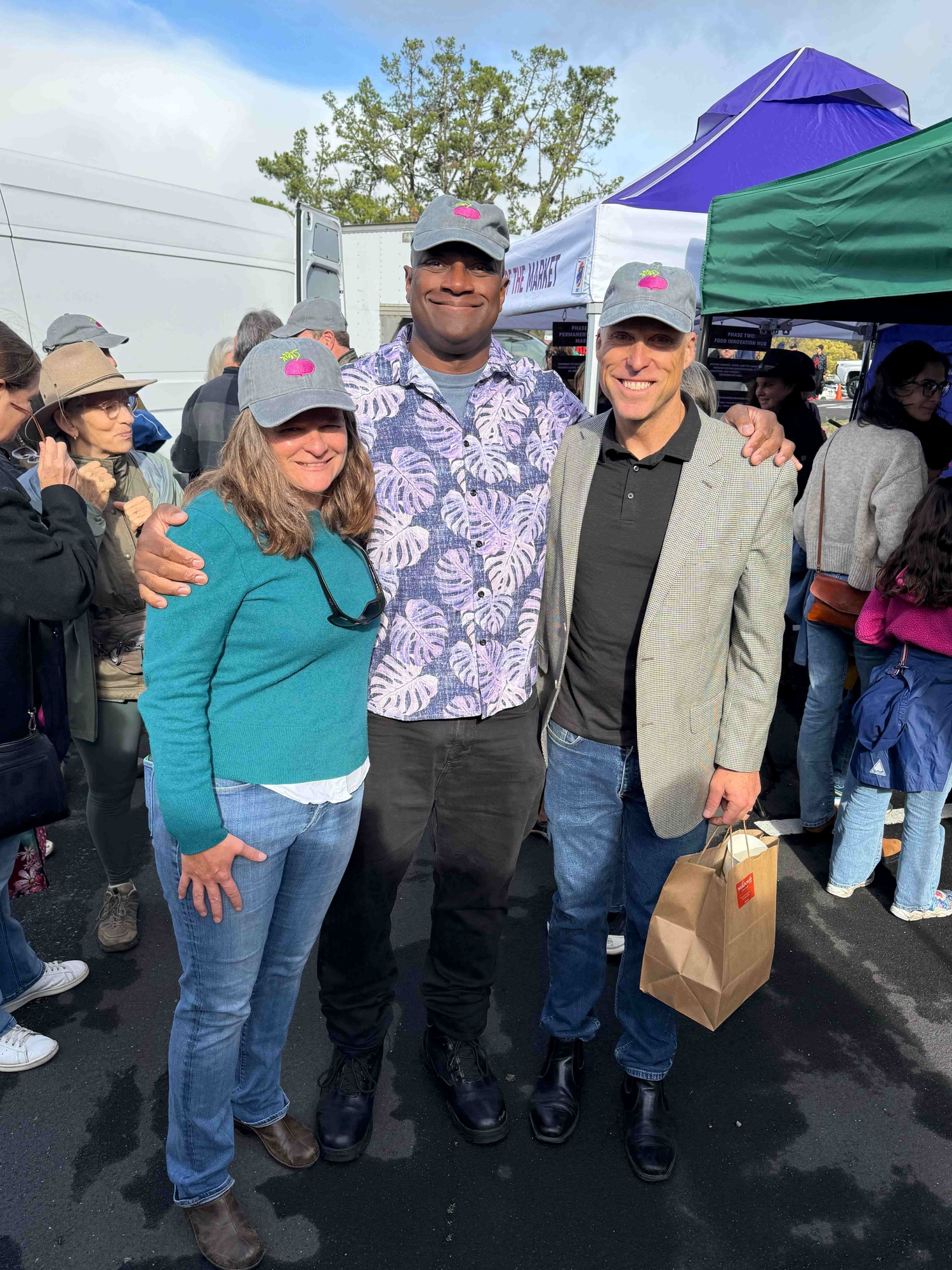Farmers Market with Supervisor Colbert and Derek Johnson smiling with matching baseball caps with farmers market logo