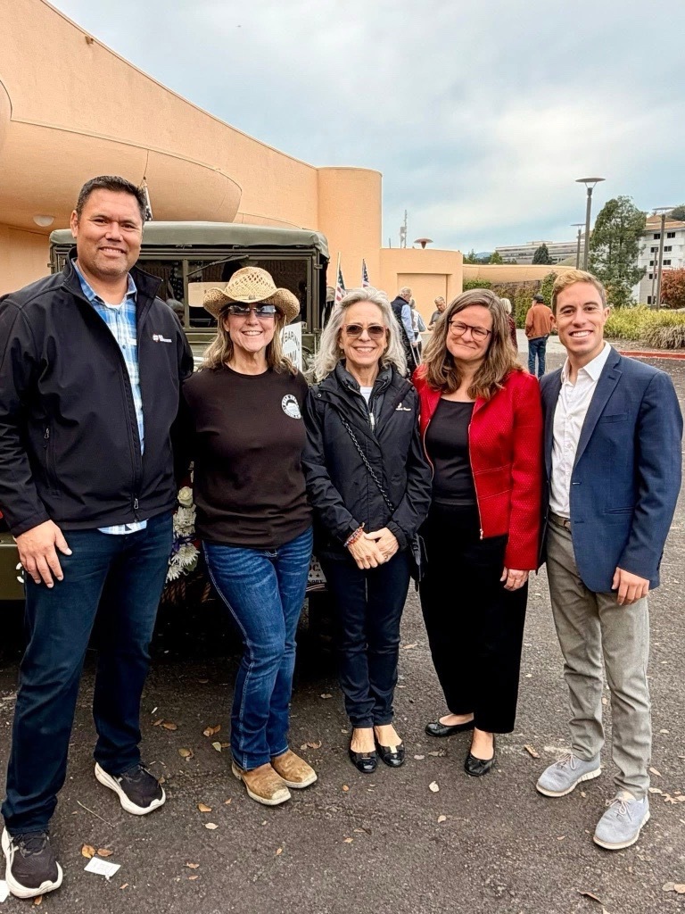 Mary, Eli Beckman, Patty Garbarino, and other smiling in front of Veterans Memorial Auditorium