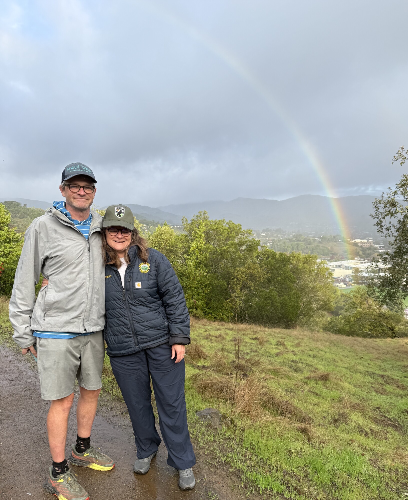 Mary and her brother pose in front of rainbow on hike