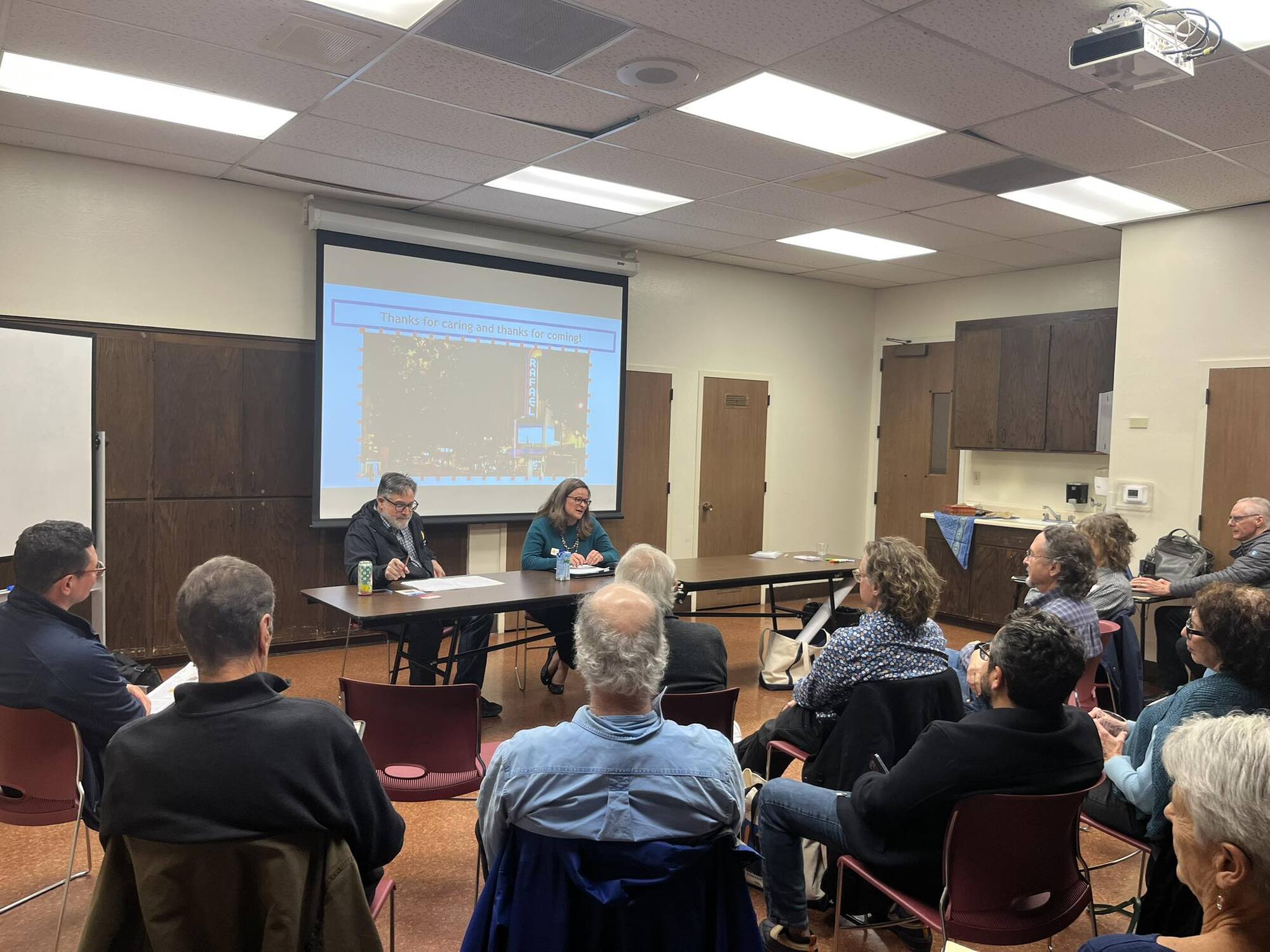 Mary and Dennis seated at a table speaking to seated audience