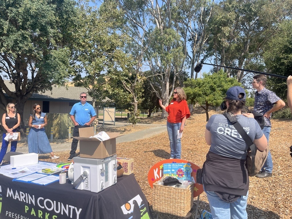 Mary speaking to people outside next to a Marin Parks table