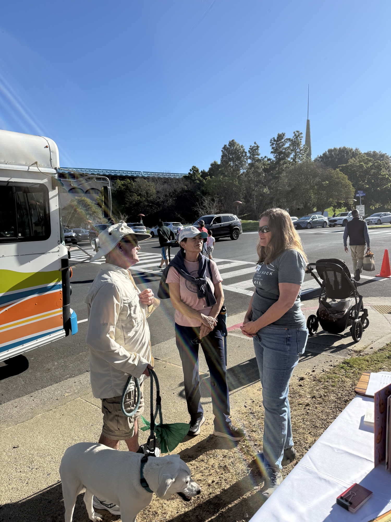 Mary chatting with two neighbors and their dog at the farmers market next to Bookmobile