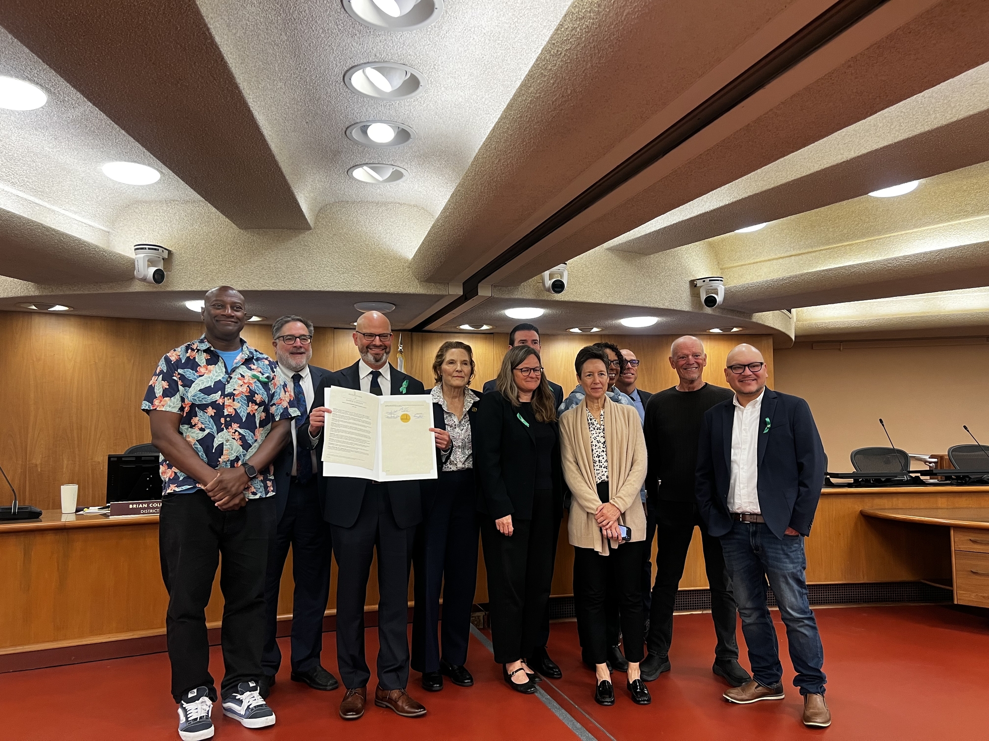Board and Health and Human Services staff smile holding May Mental Health Month resolution
