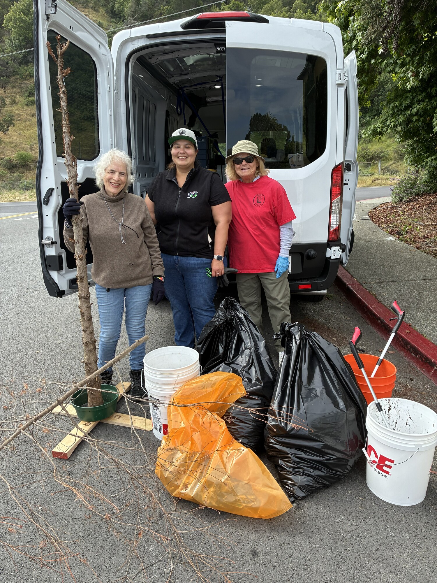 Linda Levey, Crystal Martinez and Mary Hanley with trash in front of van