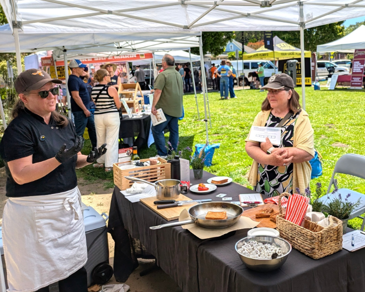 A booth with electric cooking wear and two ladies smiling toward camera