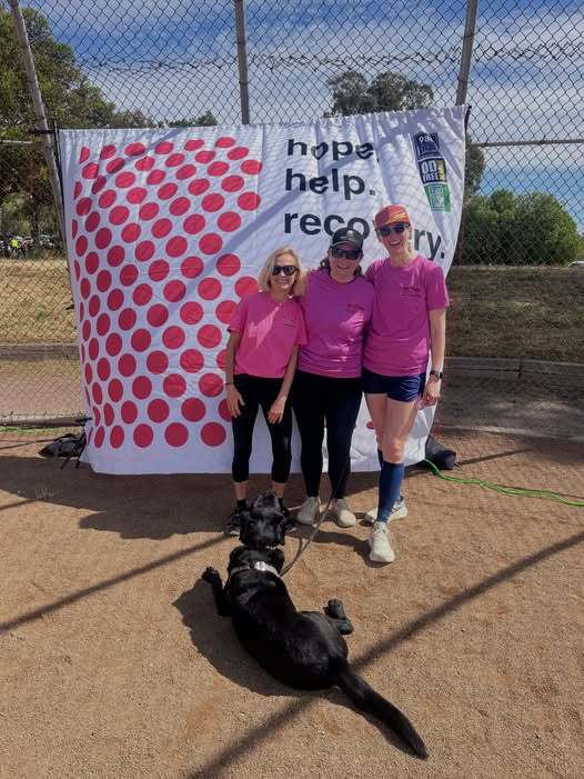 Mary pictured with Nancy Vernon and Amy Probst with pink background and dogbanner in the background